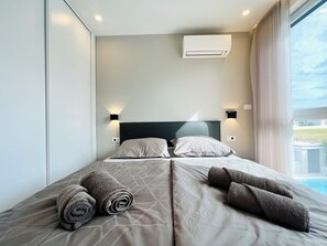 Ein Hotelzimmer mit einem Bett, zwei Wandleuchten, einer Klimaanlage und Blick ins Freie.