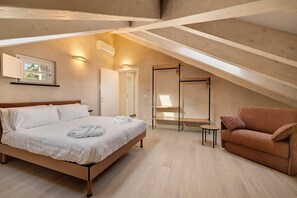 A bedroom with a bed, a sofa, a small table, a wardrobe, and a window.