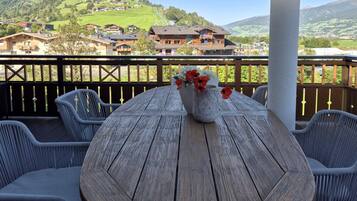 Ein Holztisch mit einer Blumenvase auf einem Balkon mit Blick auf eine gebirgige Landschaft.