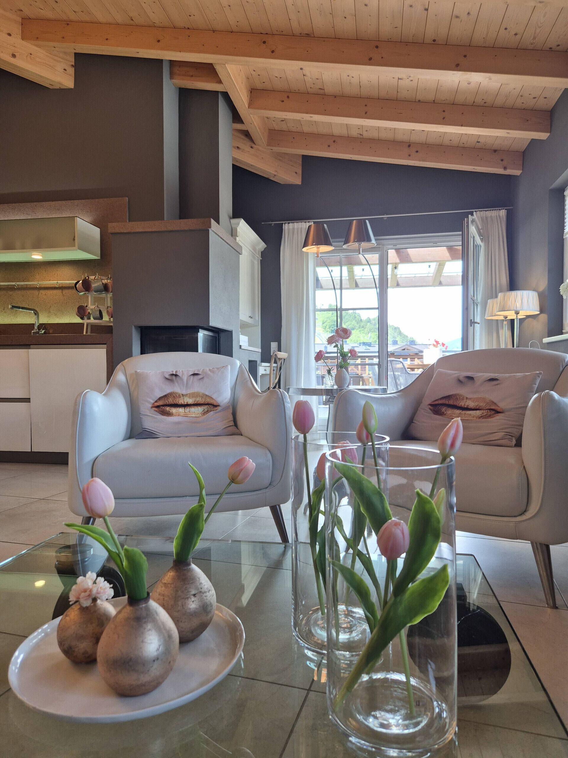 Een moderne woonkamer met een bank, een glazen salontafel en uitzicht op het groen.