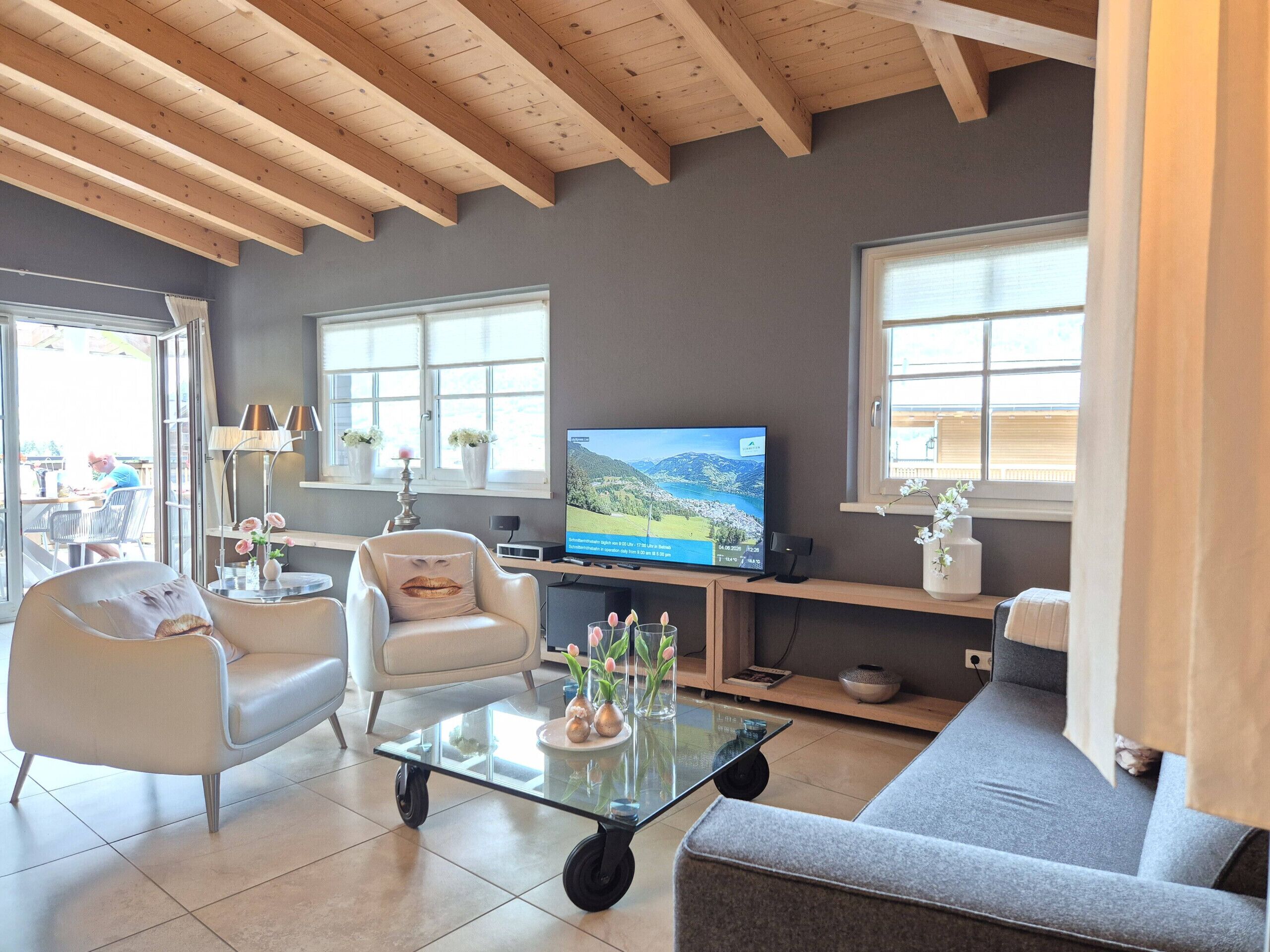 A living room with a television, seating, and a view of the outdoors.