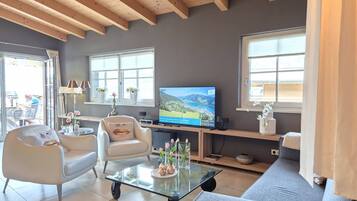 A living room with a television, seating, and a view of the outdoors.