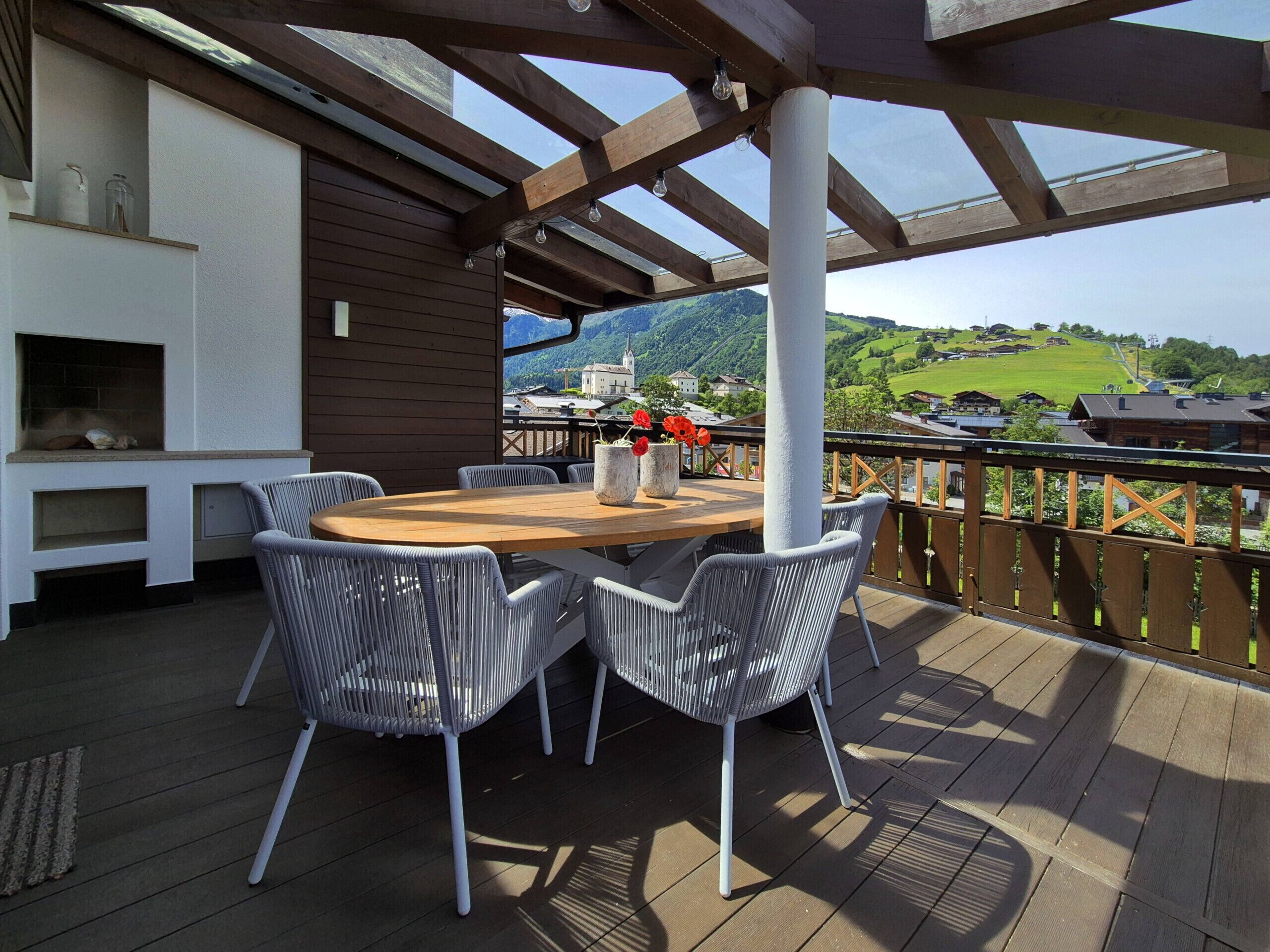 An outdoor patio with a wooden table and wicker chairs, overlooking a scenic landscape.
