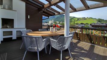 An outdoor patio with a wooden table and wicker chairs, overlooking a scenic landscape.
