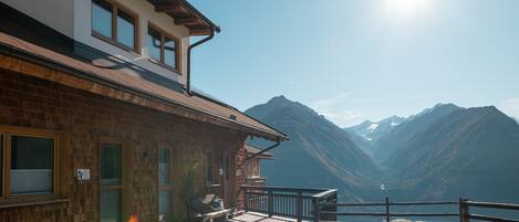 A wooden cabin with a balcony overlooking a mountain lake.