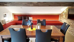 A modern dining area with a wooden table, black chairs, and a red cushioned bench.