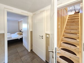 A bedroom with a bed, a white wardrobe, and a wooden staircase.
