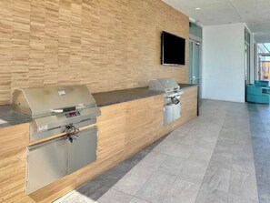 Ein Empfangsbereich mit einer Holzwand, einem Flachbildfernseher und einer Theke mit zwei integrierten Grillstationen.