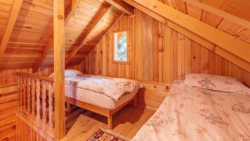 A wooden cabin with a loft bedroom, a small window, and a wooden staircase.