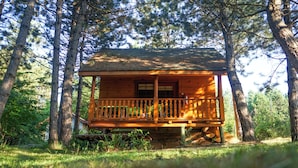 A wooden cabin with a balcony, surrounded by trees.
