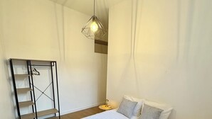 A bedroom with a large bed, a hanging light fixture, a side table, and a wooden floor. - T3 hyper center near train station (Bourgoin-Jallieu)