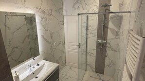 A modern bathroom with a glass-enclosed shower, a large mirror, and a marble-tiled floor. - T3 hyper center near train station (Bourgoin-Jallieu)