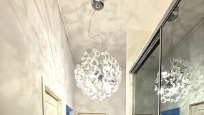 A hallway with a wooden floor, white walls, a telephone, and a large mirror reflecting a ceiling light fixture. - T3 hyper center near train station (Bourgoin-Jallieu)