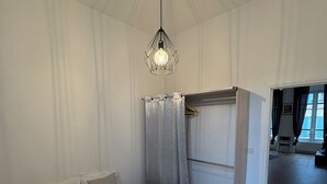 A hotel room with a bed, a hanging light fixture, a wardrobe, and a view of the outside. - T3 hyper center near train station (Bourgoin-Jallieu)