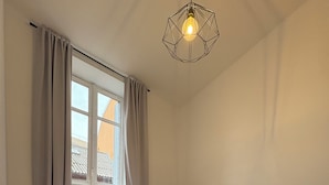 A hotel room with a bed, a round table with a lamp, a remote control, and a window with curtains. - T3 hyper center near train station (Bourgoin-Jallieu)