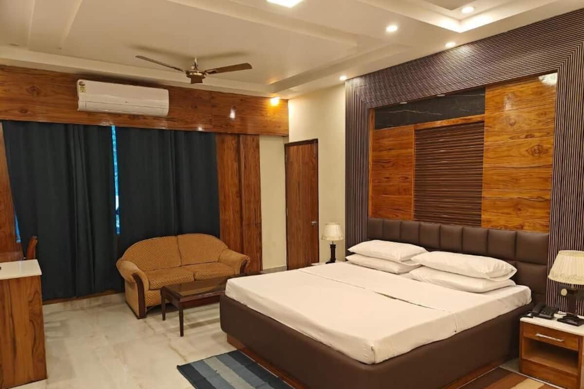 A bedroom with a bed, a sofa, a desk, and a ceiling fan.