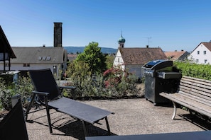 Ein Sitzbereich im Freien mit Grill, Bank und Stuhl.
