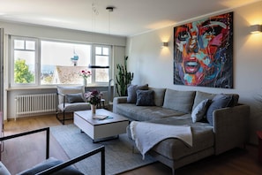 Ein modernes Wohnzimmer mit einer Couch, einem Couchtisch und einem großen abstrakten Gemälde.