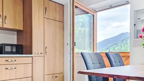 A modern kitchen with wooden cabinets, a microwave, and a dining area with a table and chairs. - Apartment Maria by Interhome (Kaprun)
