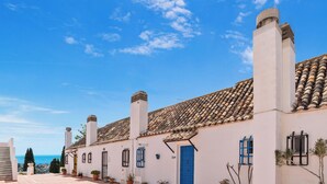 A white building with a tiled roof, a blue door, and multiple chimneys. - Charming 1BR in Pueblo Mijitas with Terrace by Mijas Golf (Mijas)