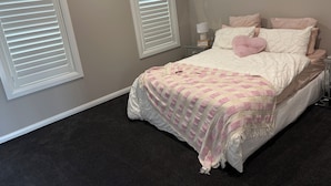 Una camera da letto con un letto, due comodini, una lampada da parete e un tavolino.
