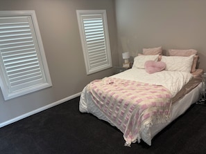 Ein Schlafzimmer mit einem Bett, zwei Nachttischen, einer Wandlampe und einem kleinen Tisch am Bett.
