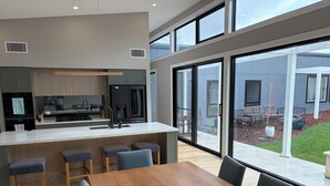 Una cucina moderna con isola centrale, sgabelli da bar e zona pranzo con tavolo e sedie in legno.