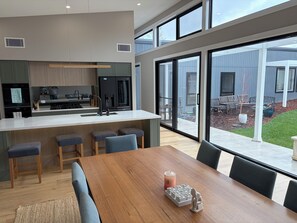 Eine moderne Küche mit einer zentralen Kochinsel, Barhocker und einem Essbereich mit Holztisch und Stühlen.