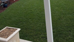 Una casa moderna con un portico coperto, un prato curato e una statua nel giardino.