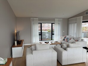 Ein modernes Wohnzimmer mit einer Sofagarnitur, einem Flachbildfernseher und einem Couchtisch.