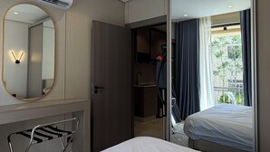 A hotel room with a bed, a mirror, a wardrobe, a hanging laundry rack, and a view of the outside. - 210 Tara-jre Jabal Al Lweibdeh With Stunning View (Amman)