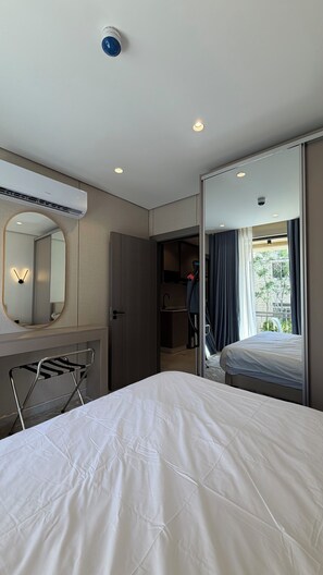 A hotel room with a bed, a mirror, a wardrobe, a hanging laundry rack, and a view of the outside. - 210 Tara-jre Jabal Al Lweibdeh With Stunning View (Amman)