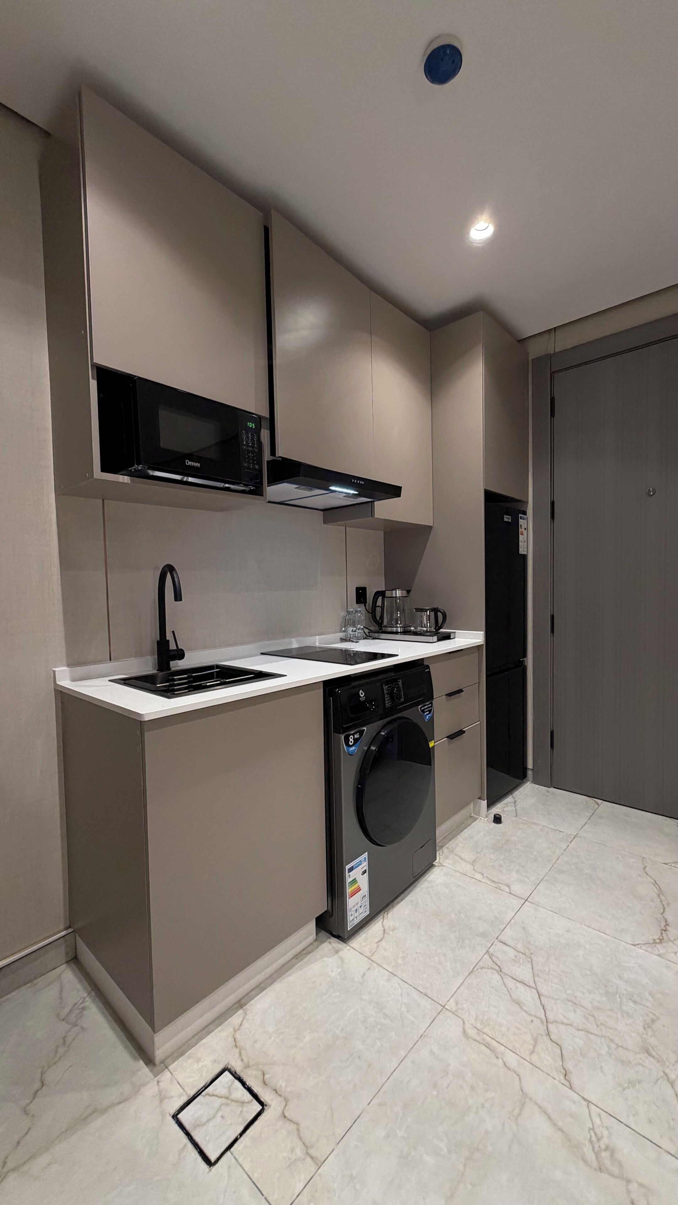A compact kitchen with a built-in microwave, a coffee maker, a dishwasher, and a washing machine.