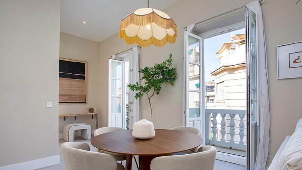 A dining area with a round table, chairs, a hanging light fixture, a potted plant, and a view through an open door. - Bright Apartment in Granada Center San Anton 301 (Granada)