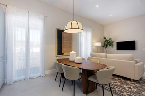 A modern living room with a wooden dining table, four chairs, a sofa, a TV, and a large window with sheer curtains. - Lovely apt With Balcony in Granada San Anton 303 (Granada)