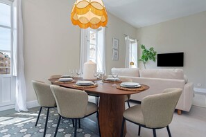 Een eetruimte met een houten tafel, vier stoelen en een hangende lamp.