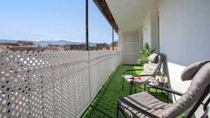 A balcony with a view of snow-capped mountains, a white lattice fence, and a seating area with a table and chairs. - Luxurious 3 bd Apartment in Granada San Anton 302 (Granada)