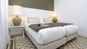 A neatly made bed with a grey blanket, two bedside lamps, and a patterned floor. - Luxurious 3 bd Apartment in Granada San Anton 302 (Granada)