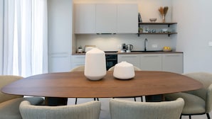 A modern kitchen with white cabinets, a wooden dining table, and two chairs. - Luxurious 3 bd Apartment in Granada San Anton 302 (Granada)