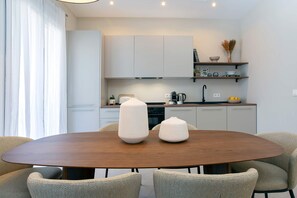 A modern kitchen with white cabinets, a wooden dining table, and two chairs. - Luxurious 3 bd Apartment in Granada San Anton 302 (Granada)