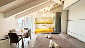 Una camera del dormitorio con letti a castello, un tavolo con sedie e angolo cottura.