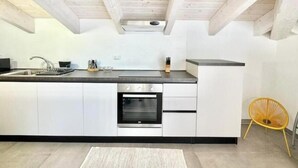 Una cucina moderna con mobili bianchi, un forno in acciaio inossidabile e un piano di lavoro nero.