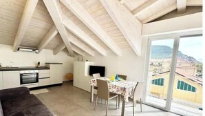 Un appartamento moderno con cucina, zona pranzo e ampie porte scorrevoli in vetro su un balcone.