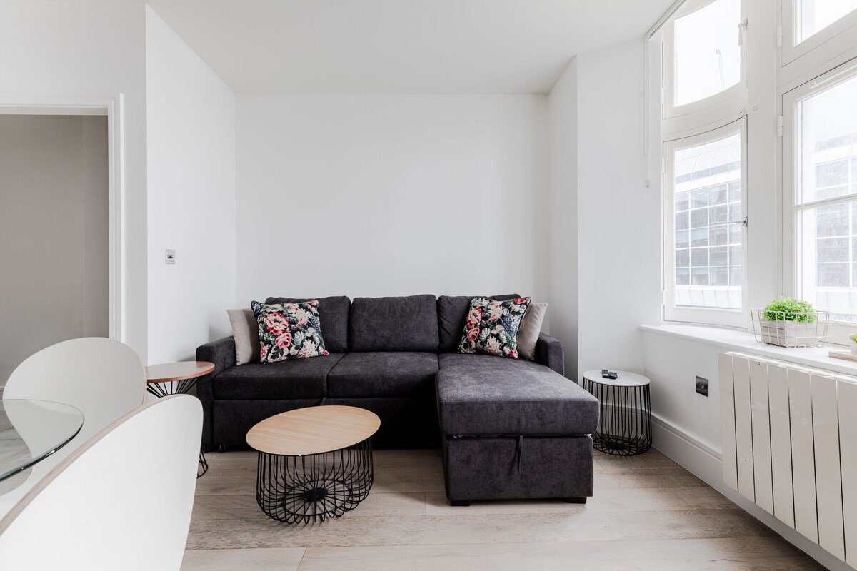 A modern living room with a sectional sofa, a round coffee table, and a small side table.