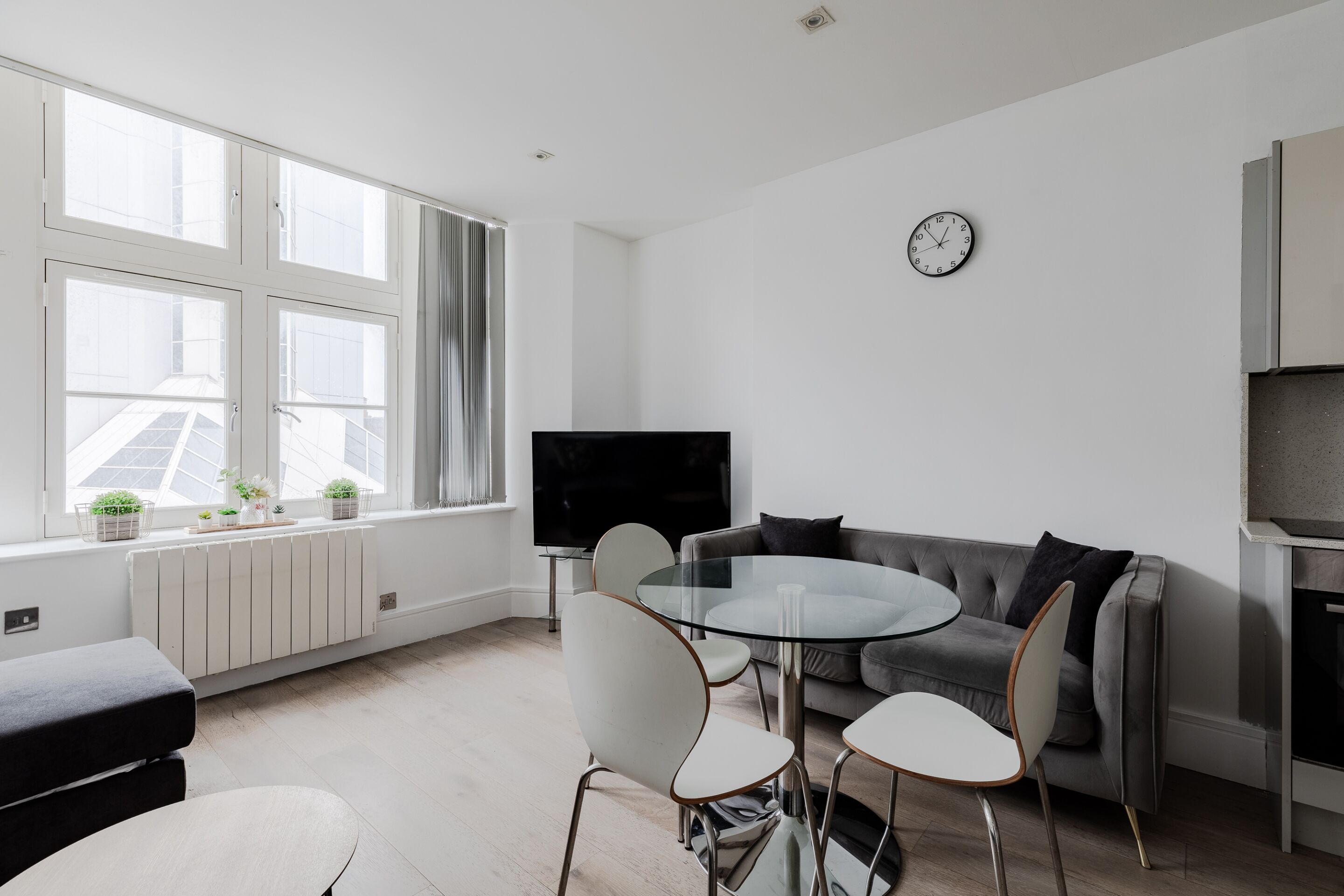 A modern living room with a sofa, TV, and dining table with chairs.
