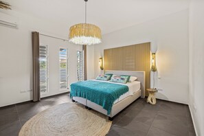 Ein Schlafzimmer mit Bett, einer Hängelampe, einem Nachttisch und Blick ins Freie.