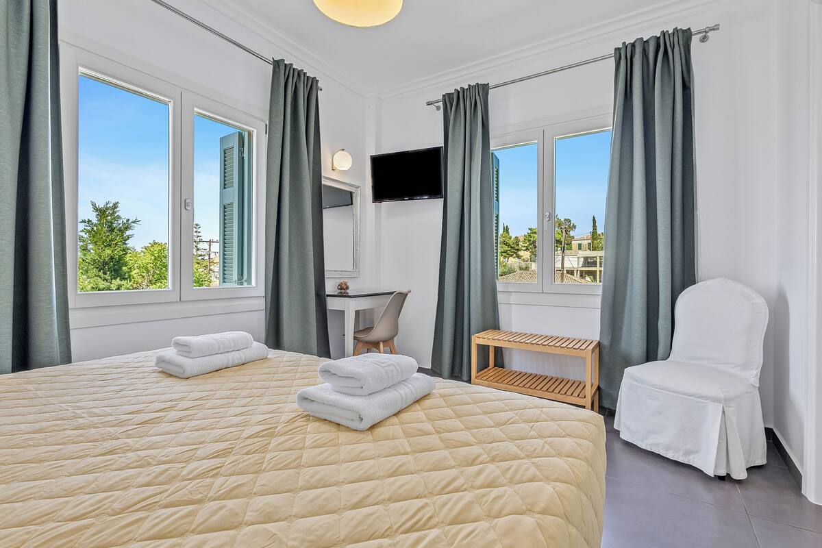 Una habitación de hotel con una cama grande, un escritorio, una silla y un televisor.