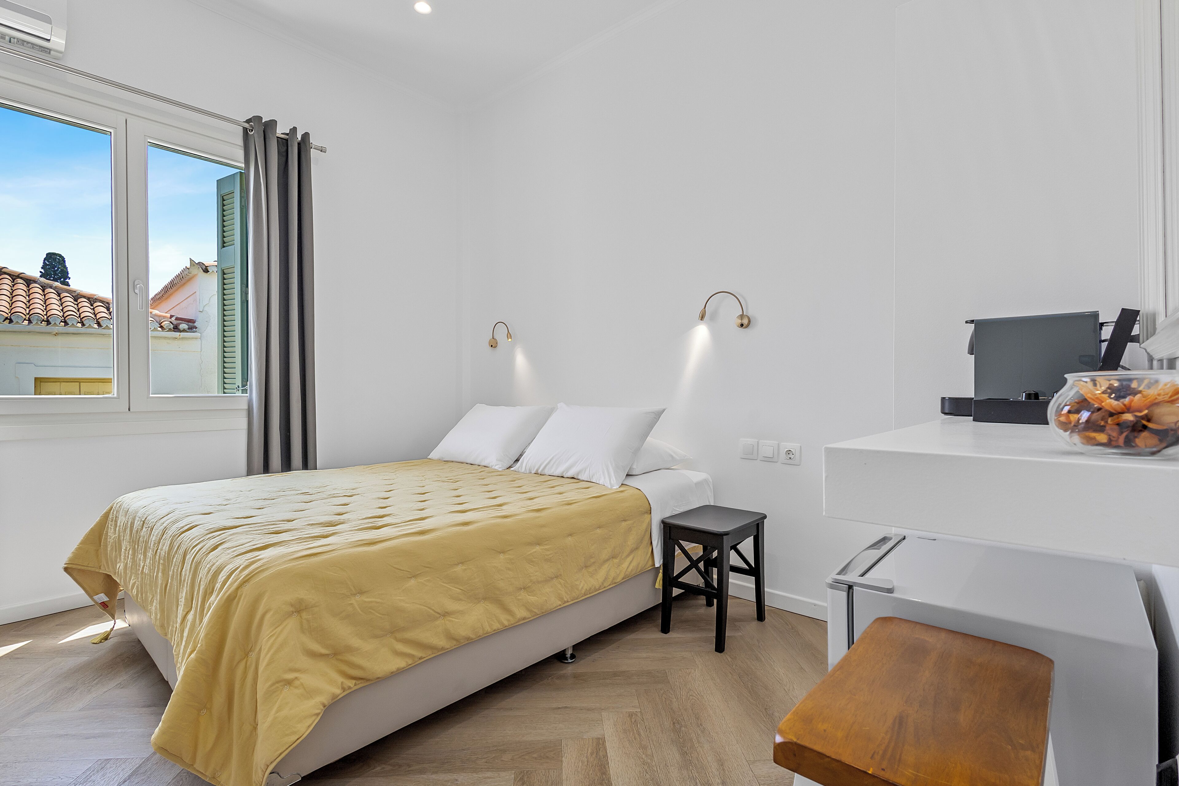 A modern bedroom with a bed, a desk, and a view of the outside.