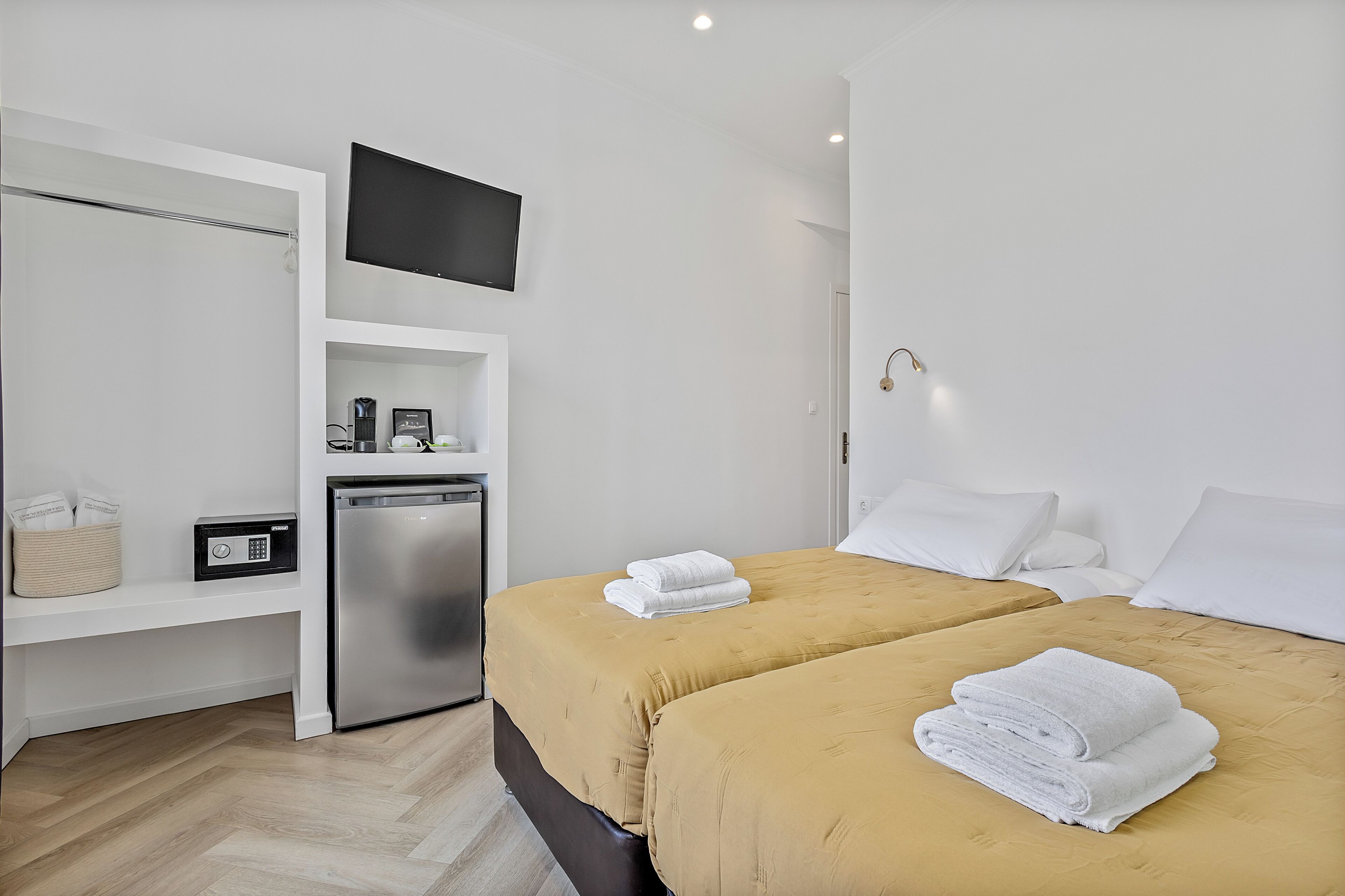Quarto de hotel com duas camas, televisão, mini-geladeira e cafeteira.