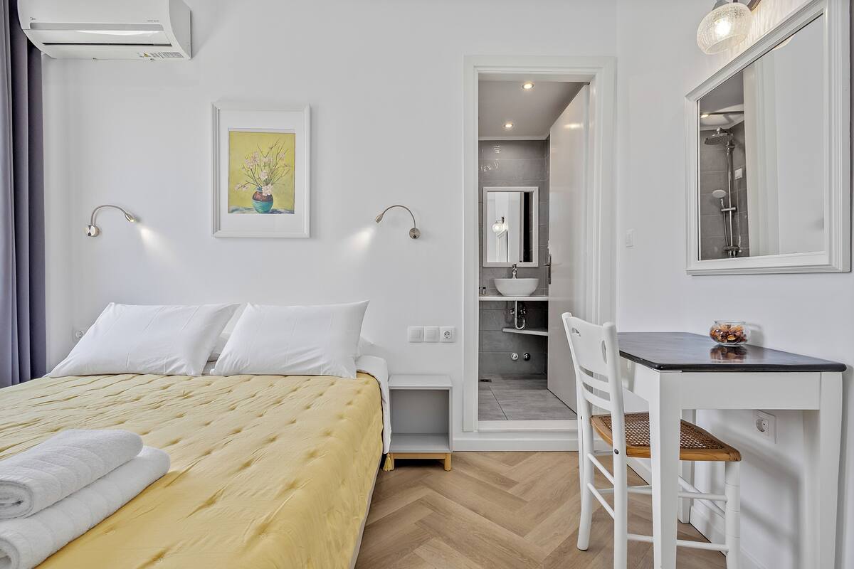 Habitación de hotel con cama, escritorio, silla, baño y un cuadro en la pared.